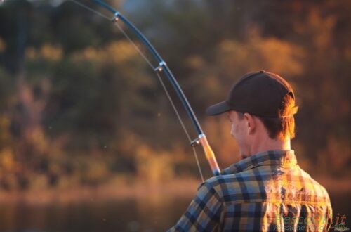 pescatore in riva con canna da pesca illuminato da un sole caldo
