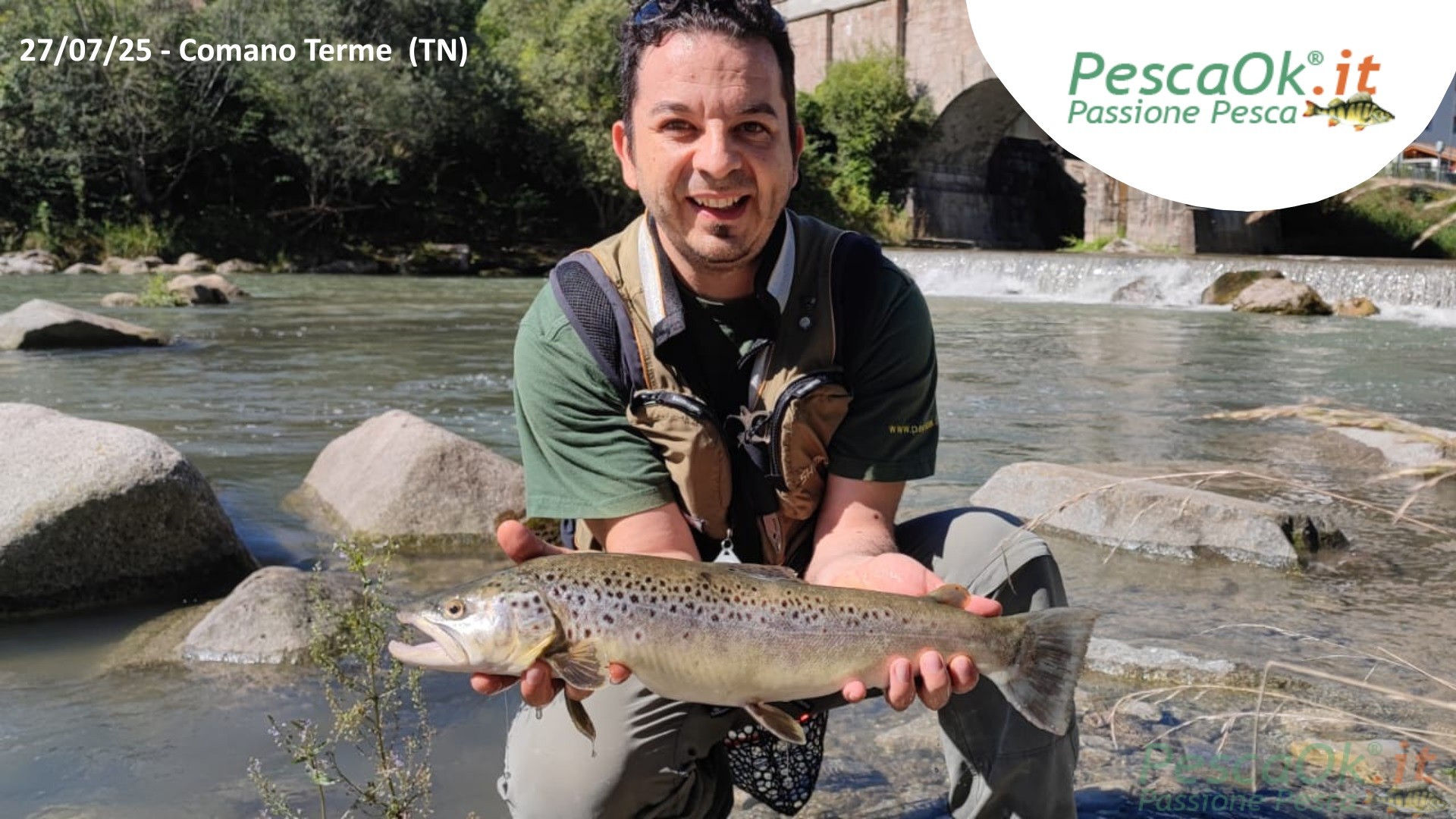 Pescatore con in mano trota feria appena pescata nel fiume